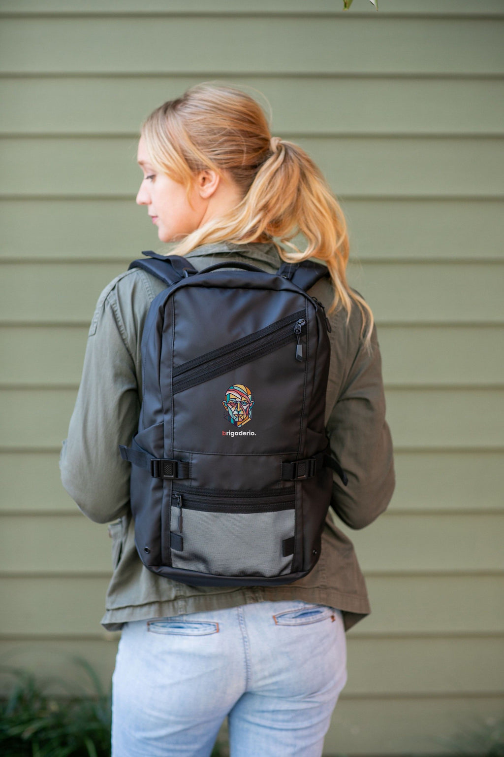 Person wearing a black backpack with 'ICON' branding against a beige wall.