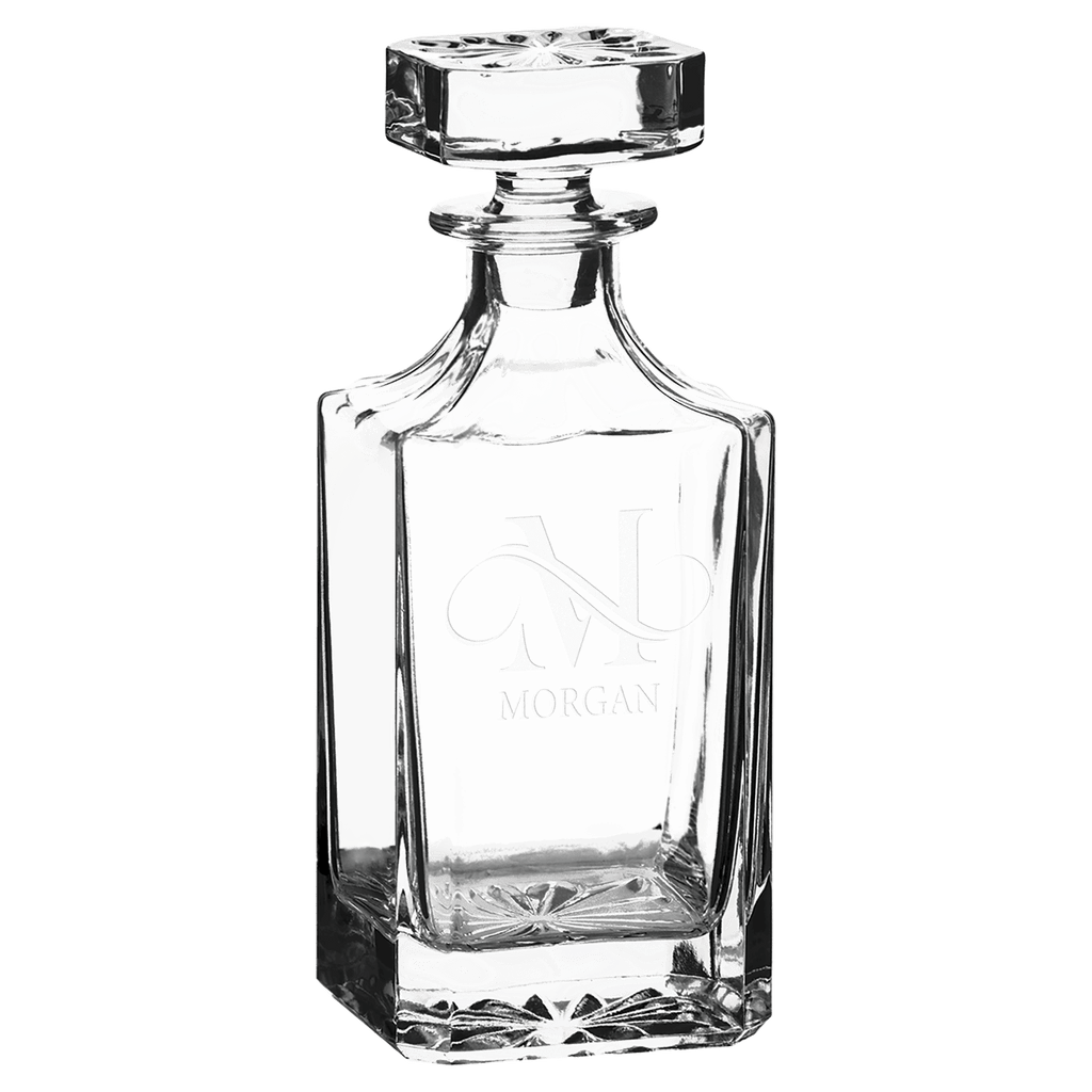Clear glass decanter with engraved design on a green background