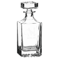 Clear glass decanter with engraved design on a green background