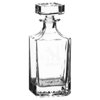 Clear glass decanter with engraved design on a green background