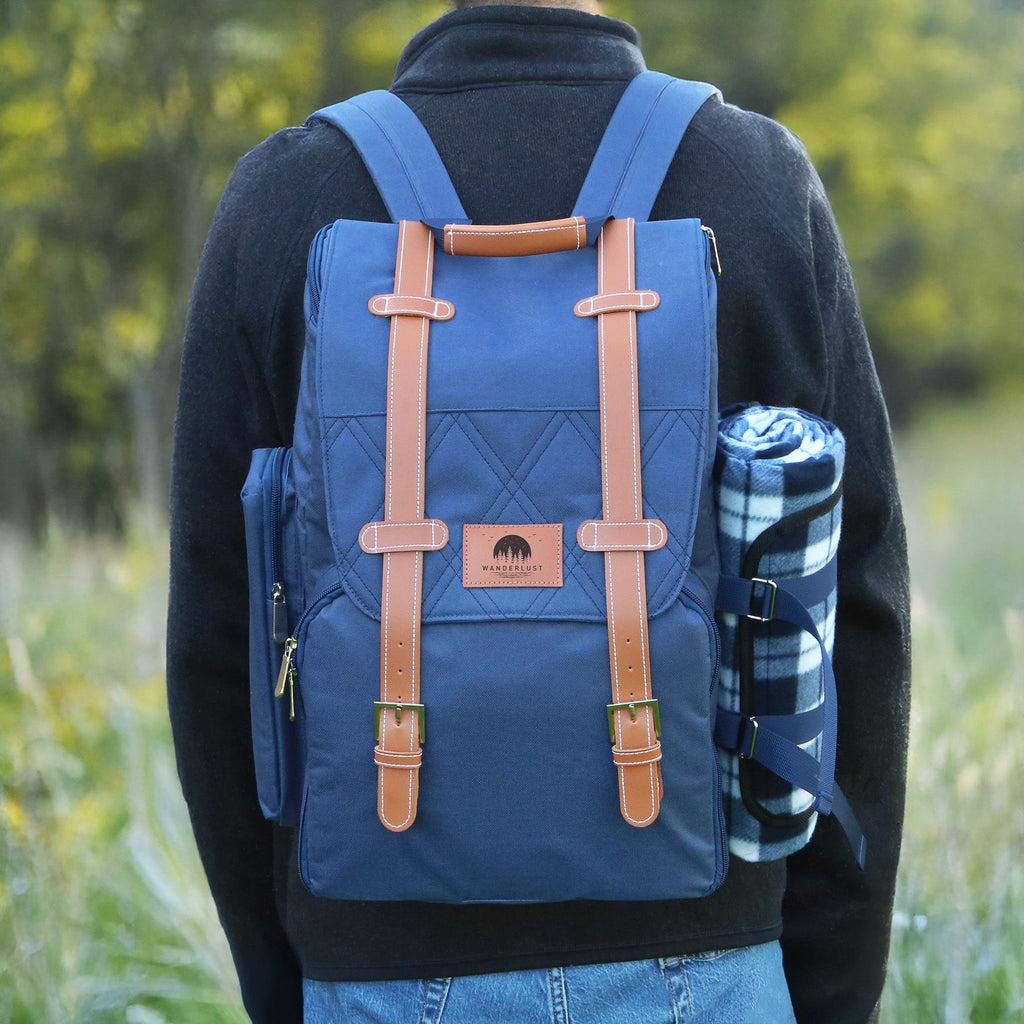 Person wearing a blue backpack with brown straps and a branded leather patch in a natural setting