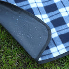 Blue and white checkered picnic blanket with a black border on grass