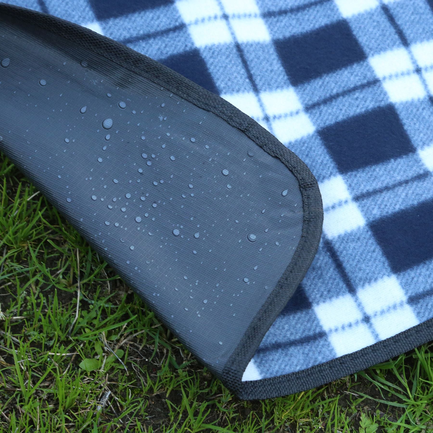 Blue and white checkered picnic blanket with a black border on grass