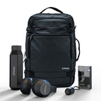 Black backpack with Spaced branding, including a water bottle, headphones, and a small device on a white background.