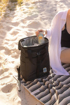 Person on a beach with a black cooler bag and a can of Lipton Ice Tea.