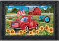 Red truck with American flag, barn, and tractor in a scenic setting with sunflowers.
