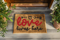 Doormat with 'love lives here' text on a wooden porch