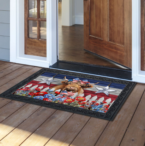 Decorative doormat with a patriotic design featuring an American flag, flowers, and a dog on a wooden deck.