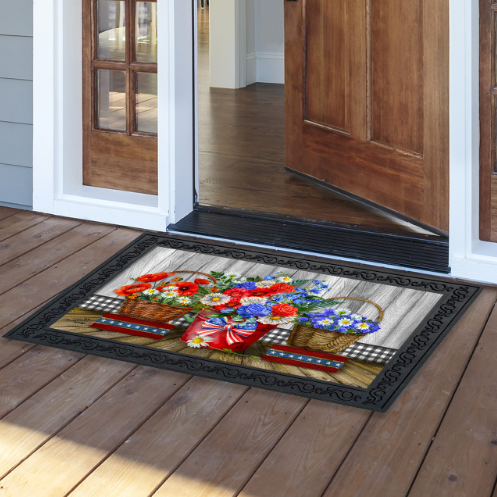 Decorative doormat with floral design on a wooden floor outside a house.