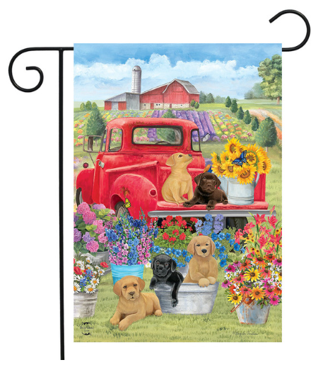 Decorative garden flag with a red truck, puppies, and flowers in a field setting.