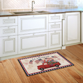 Decorative doormat with a red truck and 'Welcome' text on a wooden floor in a kitchen.