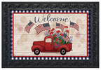 Decorative mat with a red truck, American flags, and flowers on a wooden background with 'Welcome' text.