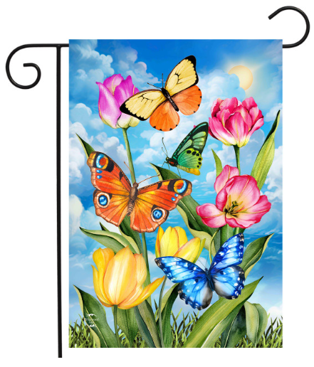 Decorative garden flag with colorful butterflies and tulips against a blue sky.