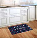 Kitchen with a 'WELCOME' mat featuring stars on a wooden floor.