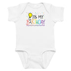 White baby onesie with colorful 'It's My Birthday' text and balloon design on a white background