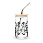 Glass tumbler with floral design, wooden lid, and metal straw on a white background