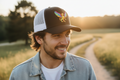 Man wearing a cap with a logo in a field during sunset