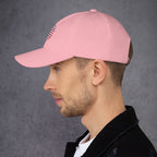 Man wearing a pink cap with a logo on a gray background