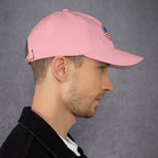 Person wearing a pink cap with a brand logo on a gray background