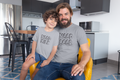 Dad and son wearing matching funny t-shirts at home that say “Need Beer” and “Need Milk”