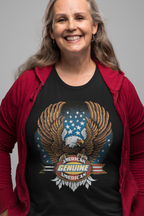 Person wearing a black t-shirt with an eagle and American flag design, smiling against a gray background