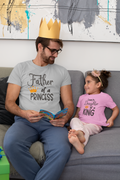 Dad reading to his daughter wearing matching Father’s Day t-shirts “Father of a Princess” and “Daughter of a King”
