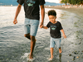 Father and son walking by a lake wearing matching shirts that say “Captain” and “First Mate”