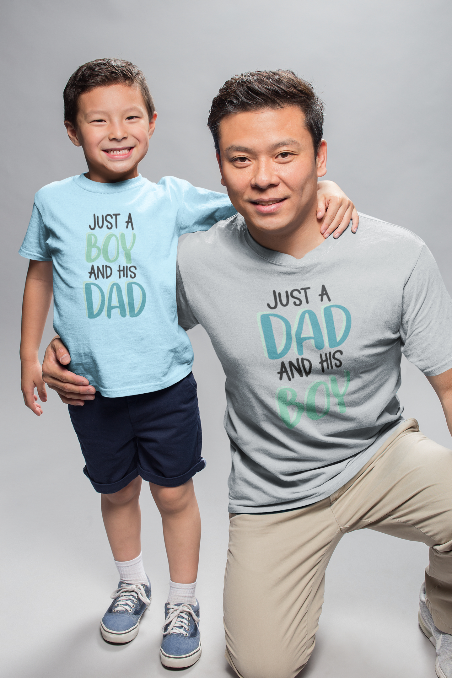 Dad and son in a photo studio wearing matching shirts “Just a Dad and His Boy” and “Just a Boy and His Dad”