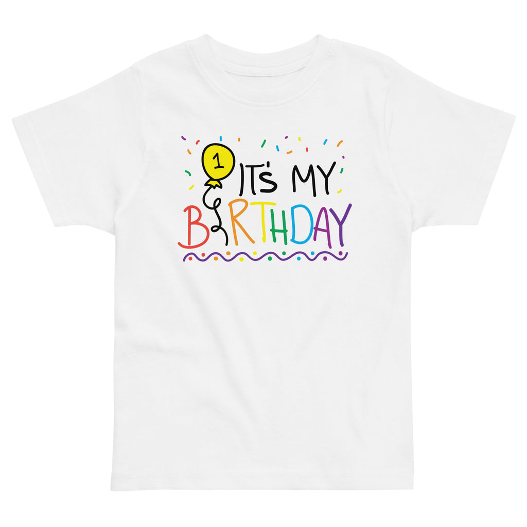 White t-shirt with colorful 'It's My 1st Birthday' text and balloon design on a white background