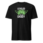 black graphic t-shirt that reads "Leveled Up to Daddy," displayed as a flat lay or lifestyle product photo — fun new dad gift for gamer dads and baby showers.