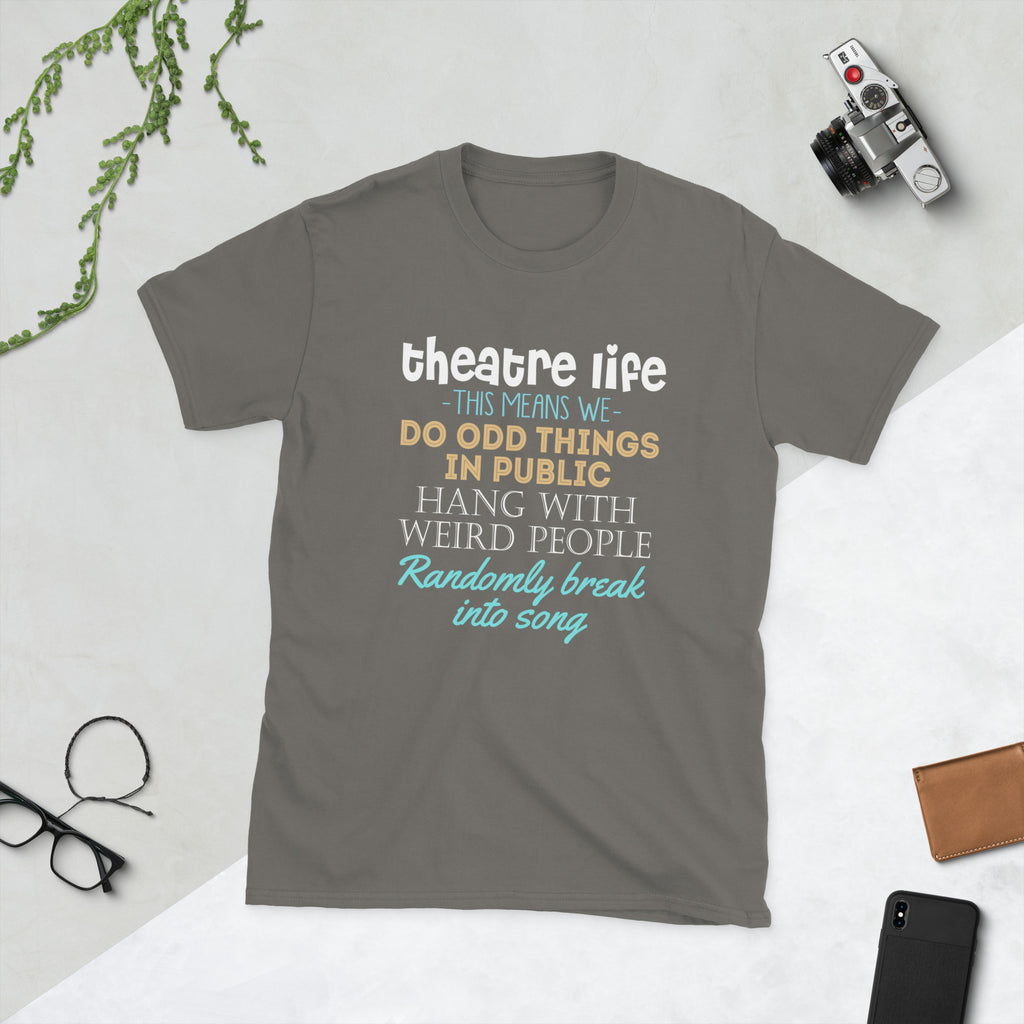 Charcoal t-shirt with colorful Theatre Life This means we do odd things in public hang with weird people randomly break into song text on a light gray surface with a camera and glasses.