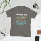 Charcoal t-shirt with colorful Theatre Life This means we do odd things in public hang with weird people randomly break into song text on a light gray surface with a camera and glasses.