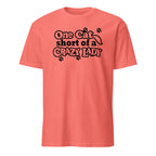 Coral t-shirt with black text 'One cat short of a crazy lady' on a white background