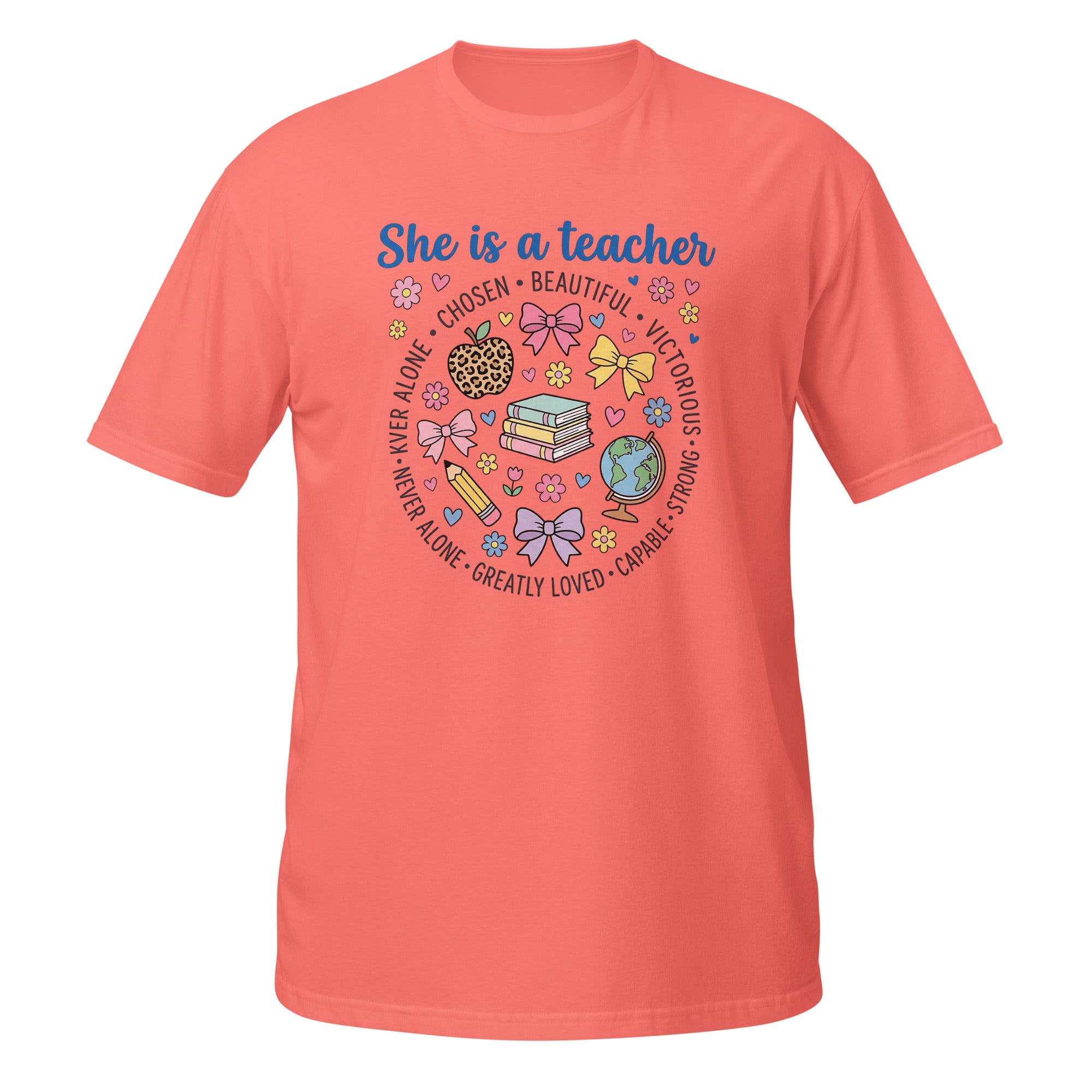 A coral pink short-sleeve t-shirt with a colorful graphic on the front that reads 'She is a teacher' surrounded by school-themed illustrations like books, bows, a globe, and flowers.