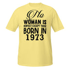 Yellow t-shirt with black text 'No woman is perfect except those born in 1973' on a white background