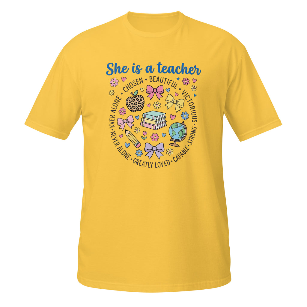 A daisy short-sleeve crewneck t-shirt featuring a colorful graphic on the front that reads 'She is a teacher' surrounded by school-themed illustrations like books, a globe, a magnifying glass, and bows.