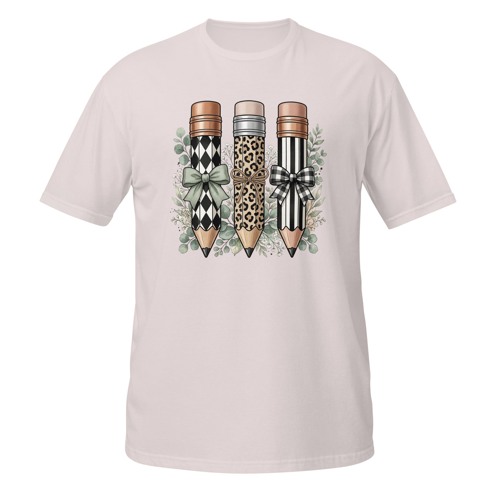 A light pink short-sleeve crewneck t-shirt featuring a graphic print of three decorative pencils with leopard, harlequin, and black-and-white striped patterns, accented with bows and green leaves.