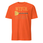 An orange short-sleeve crewneck t-shirt featuring a graphic print on the front with the text 'WITCH, PLEASE' in yellow and gray, surrounding a yellow and brown broom.