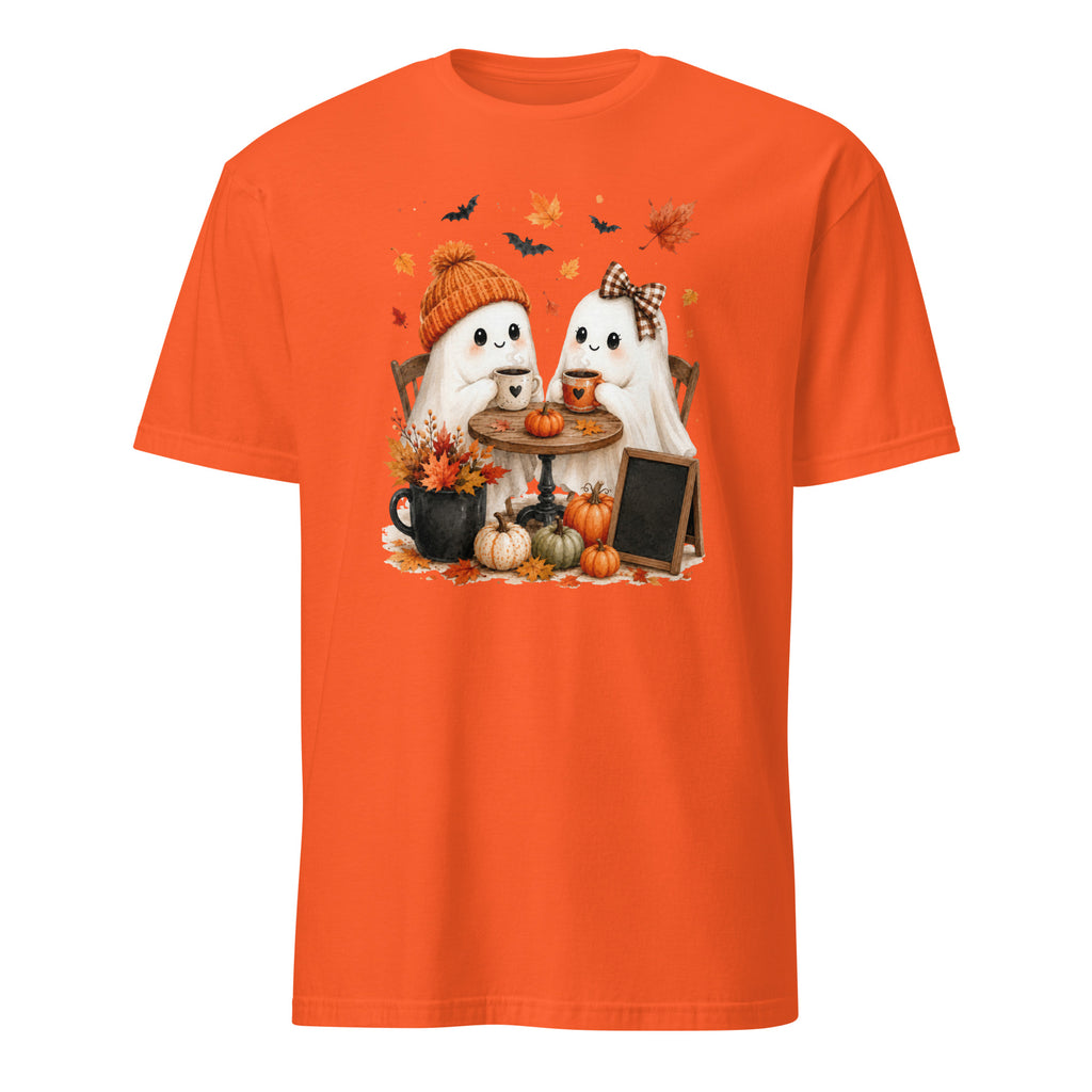 An orange short-sleeve crewneck t-shirt featuring a cute cartoon graphic of two white ghosts sitting at a small table with pumpkins, autumn leaves, and bats.