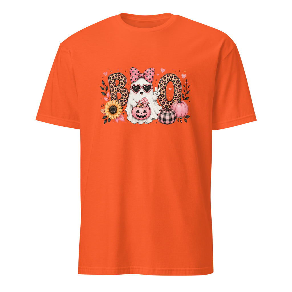 A bright orange short-sleeve crewneck t-shirt featuring a central graphic of a white dog wearing sunglasses and a pink polka-dot bow, surrounded by the word 'BOO' in leopard-print and plaid letters, with pumpkins, sunflowers, and hearts.
