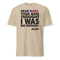 Beige t-shirt with humorous text about Pluto addressing NASA on a white background