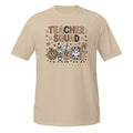 A beige short-sleeve crewneck t-shirt featuring a colorful graphic on the front that reads 'TEACHER SQUAD' above five cute cartoon characters representing school supplies and treats.