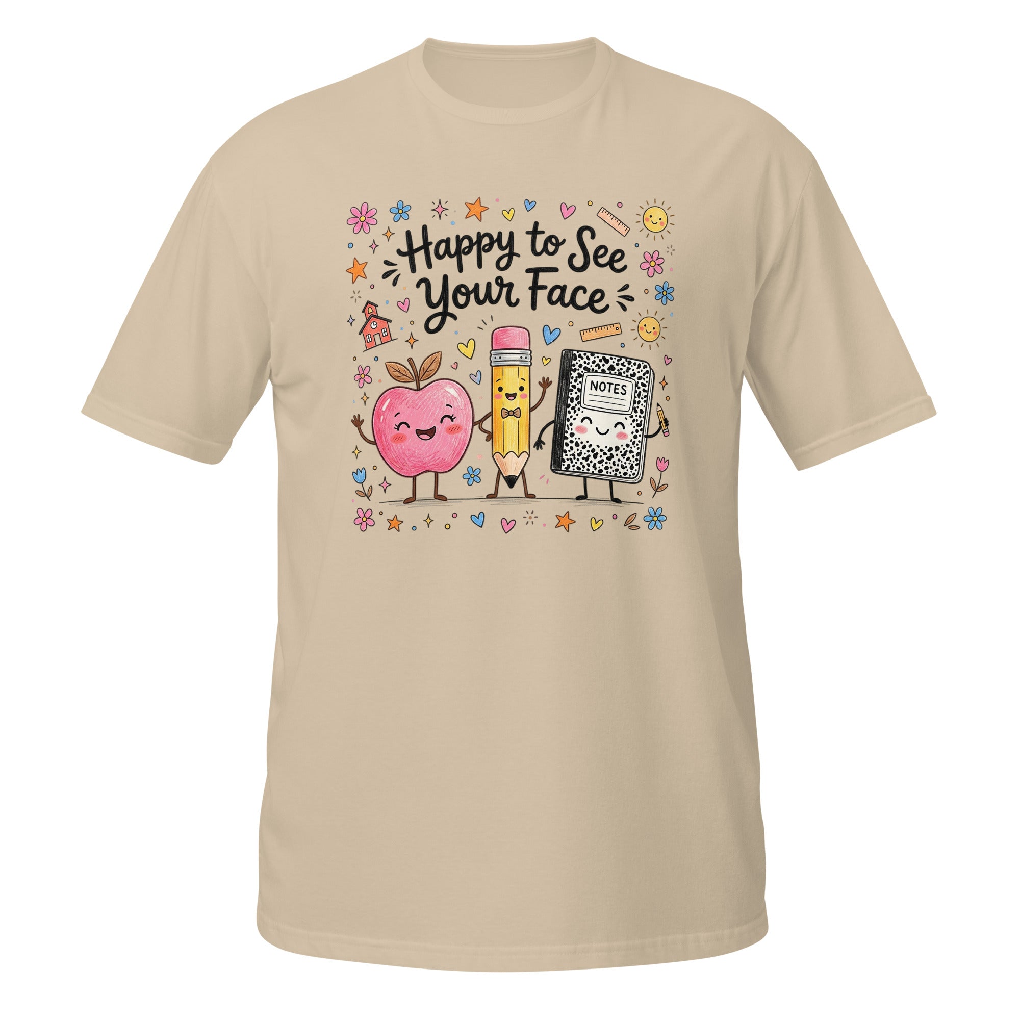 A beige short-sleeve crewneck t-shirt featuring a colorful cartoon graphic of a pink apple, a yellow pencil, and a black-and-white cat in the center, surrounded by the text 'Happy to See Your Face' and small decorative doodles.