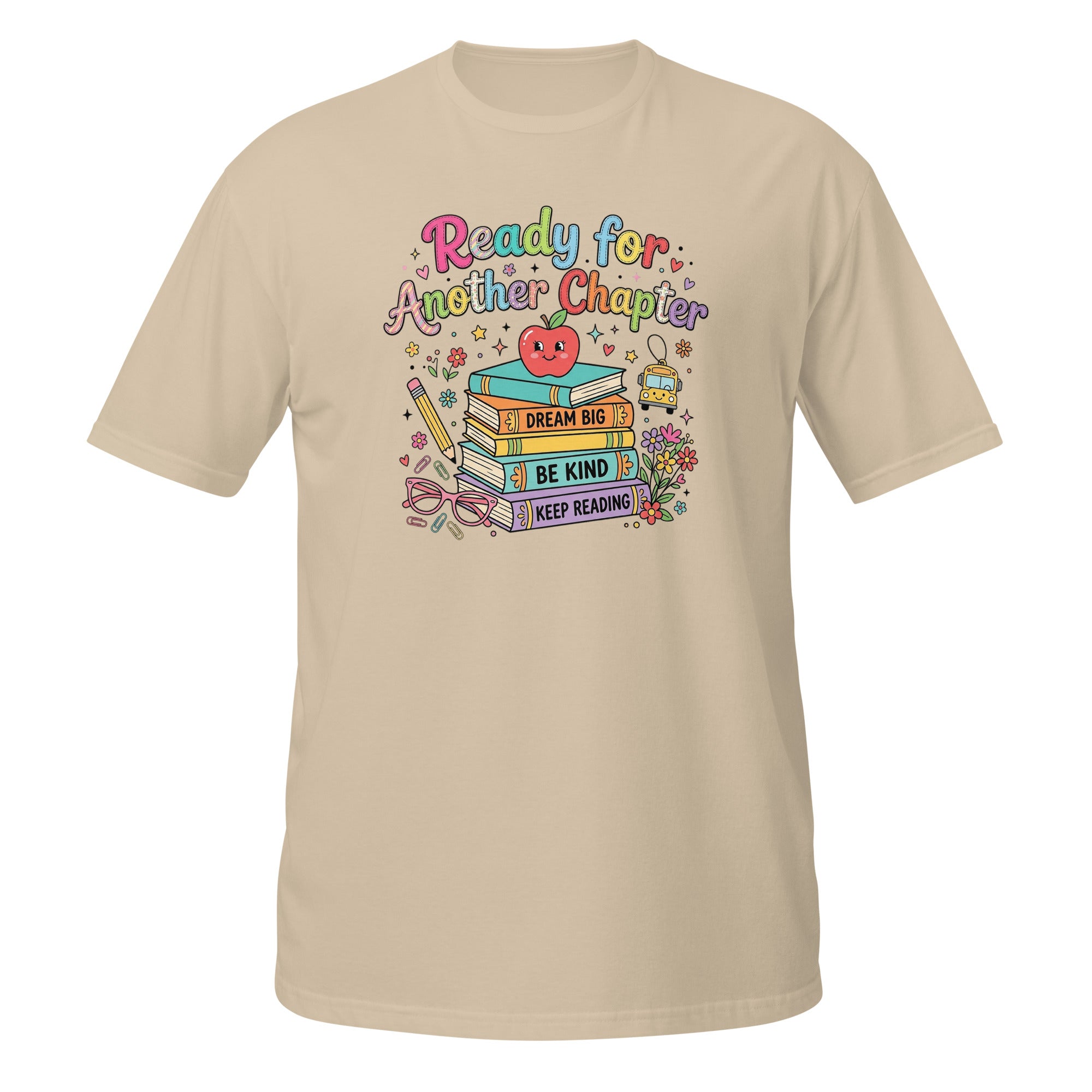 A beige short-sleeve crewneck t-shirt featuring a colorful graphic on the chest with the text 'Ready for Another Chapter' and an illustration of books, a smiling apple, and reading accessories.