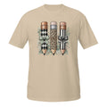 A beige short-sleeve crewneck t-shirt featuring a graphic print of three decorative pencils with diamond, leopard, and striped patterns, accented with bows and green leaves.