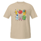 A beige short-sleeve crewneck t-shirt featuring a colorful cartoon graphic of school supplies on the chest, including a yellow pencil, red apple, yellow cup of crayons, blue glue stick, pink scissors, and green notebook.