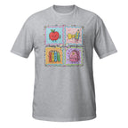 A heather gray short-sleeve t-shirt with a colorful graphic print on the front. The graphic features a four-quadrant school-themed design with a smiling red apple, a yellow bow, books, and a pink backpack, accompanied by the text 'happy to see your face!'.