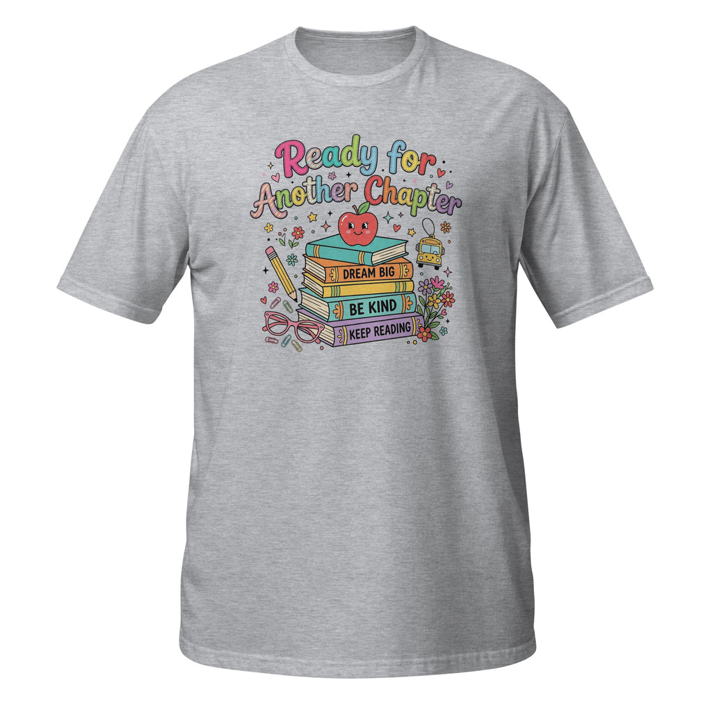 A heather gray short-sleeve crewneck t-shirt featuring a colorful graphic on the chest with the text 'Ready for Another Chapter' above a stack of books, a smiling red apple, and motivational phrases like 'I Dream It', 'Be Kind', and 'Keep Reading'.